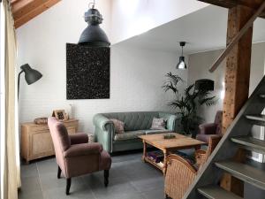 ein Wohnzimmer mit einem Sofa, Stühlen und einem Tisch in der Unterkunft Bed & Breakfast Zeeland in Renesse