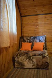 a bed in a wooden room with two orange pillows at Kućica za odmor '' Idila '' in Mitrovac