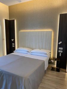 una camera da letto con un grande letto bianco con una grande testiera del letto di Hotel Gardenia a Rimini