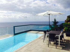 een zwembad met een tafel en een parasol bij Sea House Madeira in Garajau