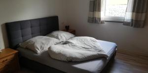 uma cama com duas almofadas com uma janela em Ferienhaus Rosenberg em Jandelsbrunn