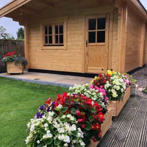 a flower garden in front of a wooden shed at Cosy Log Cabin - The Dookit - Fife in Markinch