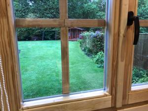 a view through a window of a yard at Cosy Log Cabin - The Dookit - Fife in Markinch