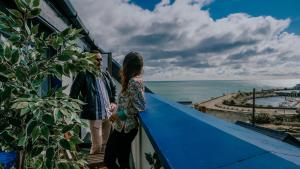 2 personnes debout sur un balcon donnant sur l'océan dans l'établissement The Wooden House - Room Only Accomodation, à Kilmore Quay