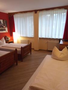 a hotel room with two beds and two windows at Hotel Atlas Sport in Garmisch-Partenkirchen