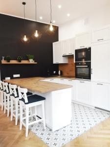 una cocina con armarios blancos y una mesa de madera con sillas. en Victoria Apartment, en Gliwice