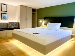 a bedroom with a large white bed with a green wall at zeitwohnhaus SUITE-HOTEL & SERVICED APARTMENTS in Erlangen