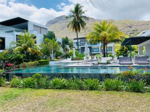 a resort with a swimming pool and palm trees at Latitude Luxury Duplex in Rivière Noire