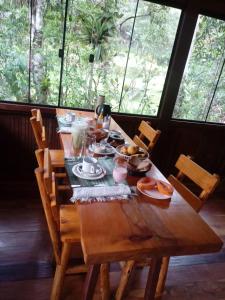 einem Holztisch mit Teller mit Lebensmitteln darauf in der Unterkunft Chalé Truta da Floresta in Visconde De Maua