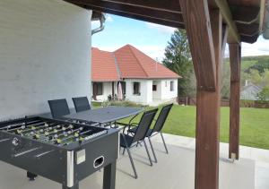 un patio con parrilla, mesa y sillas en Guest House Magyarlukafa en Magyarlukafa