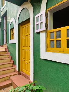 a green building with a yellow door and windows at Easy Hostels in Panaji