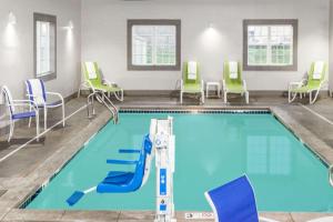 una piscina con sillas y sillas alrededor en Microtel Inn & Suites by Wyndham West Fargo Near Medical Center en West Fargo