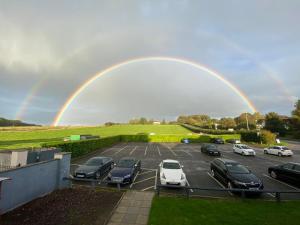 a rainbow over a parking lot with cars parked at The George Carvery & Hotel in Ripon
