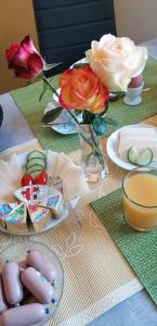 a table with flowers and a vase of roses at Pension Riverside in Leverkusen Hitdorf am Rhein - Zentral an der A1 und 59 in Leverkusen