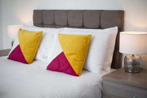 a bed with four colorful pillows on it at STOP! Stay at The Jersey in Swansea