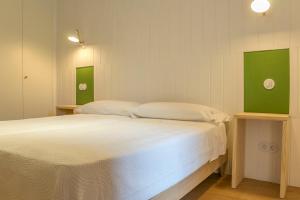Schlafzimmer mit einem Bett mit weißer Bettwäsche und grünen Akzenten in der Unterkunft Apartamento Alcuneza en Elmolinodelasal de Sigüenza in Sigüenza