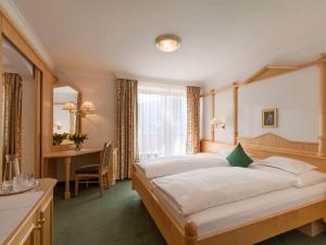a bedroom with a large bed and a desk at Antonius Hotel Garni in Lech in Lech am Arlberg