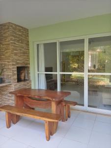 a wooden table and benches in a room with a window at Apto. Vila dos Lírios - Reserva Imbassai in Imbassai