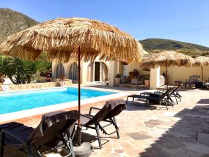 a resort with a swimming pool with chairs and umbrellas at Casa de la Piña in Hondón de los Frailes