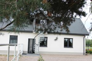 una casa blanca con techo negro en Agroturystyka Pokoje Stajnia Lidia, en Serock