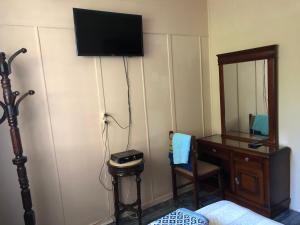 um quarto com uma secretária e uma televisão na parede em Caesar House em Alexandria