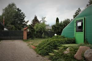uma casa verde com escadas ao lado de uma cerca em Agroturystyka Pokoje Stajnia Lidia em Serock