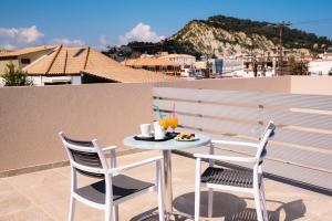 een tafel en twee stoelen op een balkon met een drankje bij KIPOI APARTMENTS in Zakynthos