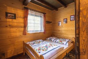 Bett in einem Blockhaus mit Fenster in der Unterkunft Siedlisko Janopole in Janopole