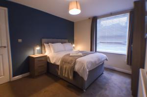 een slaapkamer met een groot bed en een raam bij #Barroon Castle Apartments by DerBnB, Traditional 1 & 2 Bedroom Apartments, Free Parking & Wi-Fi, Near East Midlands Airport & Donington Park Circuit in Castle Donington