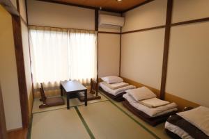 a room with two beds and a table and a window at Yoshimura ooike sense in Fujikawaguchiko