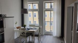 - une salle à manger avec une table, des chaises et des fenêtres dans l'établissement Ferienwohnung Busch, à Leipzig