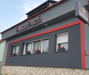 Familia Panzió & Apartmanház Győr في جيور: مبنى فيه ثلاث نوافذ وفيها ورد
