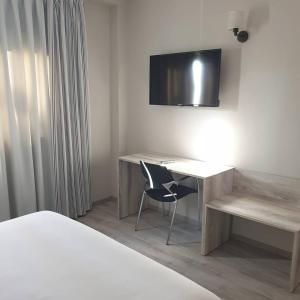 a bedroom with a desk with a chair and a television at Hotel Alcarria in Guadalajara