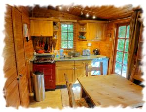 a kitchen with wooden cabinets and a table in a cabin at Blelham Tarn (Log Cabin) in Ambleside