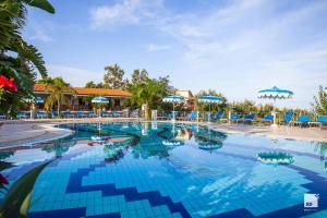 una piscina en un complejo con sillas y sombrillas azules en Tonicello Hotel Resort & SPA, en Capo Vaticano