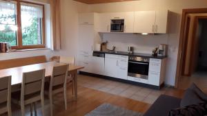 une cuisine avec des placards blancs et une table en bois avec une salle à manger dans l'établissement Haus Hagspiel, à Hittisau