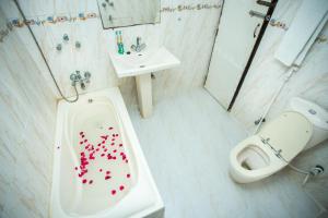 a bathroom with a toilet and a sink with red hearts on the tub at Hotel Mishuk in Cox's Bazar