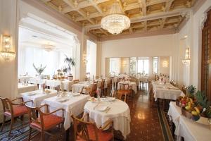 un restaurante con mesas y sillas blancas y una lámpara de araña en Genovese Villa Elena Residence en Varazze