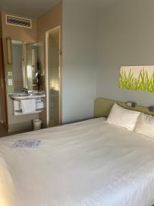 a bedroom with a large white bed with a bathroom at Ibis budget Verdun in Verdun