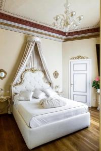 Dormitorio blanco con cama grande y lámpara de araña en Residenza d'Epoca Palazzo Borghesi en Siena