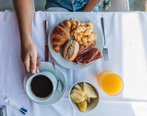 a table with a plate of breakfast foods and a cup of coffee at Aqua Natura Bay in Porto Moniz