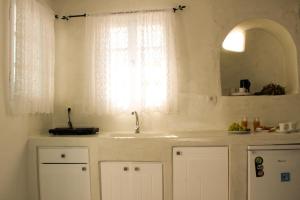 a white kitchen with a sink and a window at Casa Sigala sunset in Oia