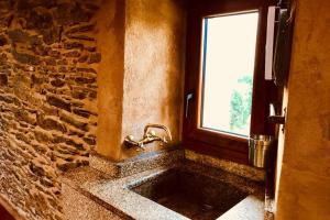 een stenen badkamer met een wastafel en een raam bij Casa rural entre Santiago Compostela y La Coruña in Ordes