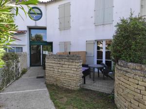 een wit huis met een bakstenen muur en een tafel bij Studio avec terrasse et parking 200m plage et commerces in La Couarde-sur-Mer