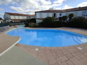 a large blue swimming pool in front of a house at Studio avec terrasse et parking 200m plage et commerces in La Couarde-sur-Mer +4 photos