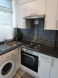a kitchen with a stove and a washing machine at Next to Aintree Golf Course in Aintree