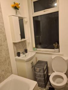 a bathroom with a toilet and a sink and a window at Next to Aintree Golf Course in Aintree