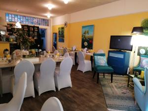 a dining room with white chairs and a long table at Pension Art Galerie in Eygelshoven