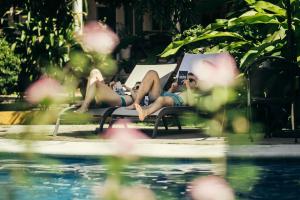 two women laying on chairs by a swimming pool at Casa Losodeli & Coworking- Adults Only in Puerto Escondido