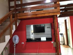 a loft bed with a flat screen tv on a red wall at Apartamento no Centro de Mongaguá in Mongaguá
